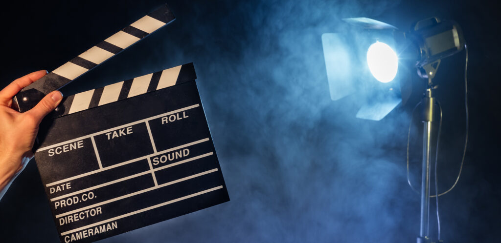 Operator holding clapperboard, studio light with claps on background. Filmmaker background