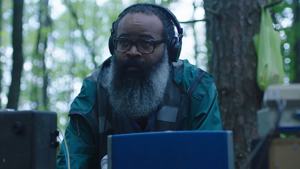Kyp Malone sits with headphones on in the forest Source - "Doors," BoulderLight Pictures