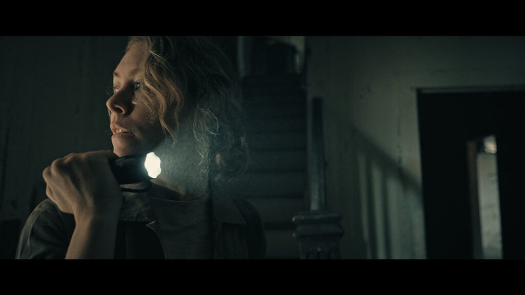 Scene featuring a woman with a flashlight from The Reclaimers