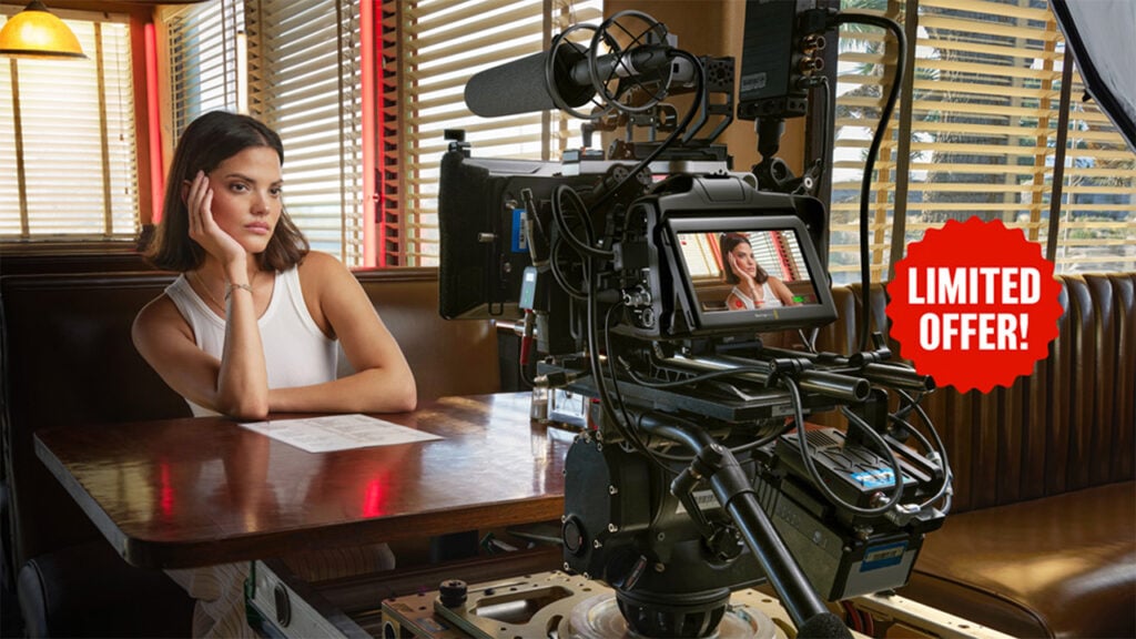 A woman in a white tank top sits in a diner while a Blackmagic Design camera films her