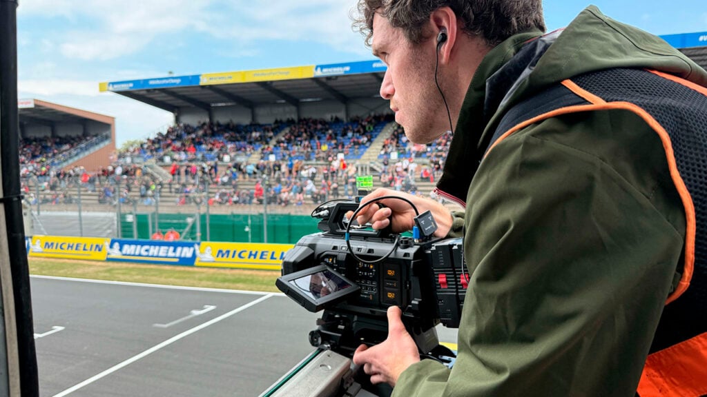 a man holds a Blackmagic camera while filming a sports event