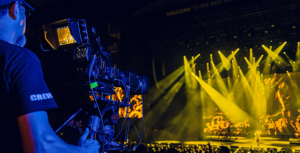A man films the Starlite Festival stage with a Blackmagic camera