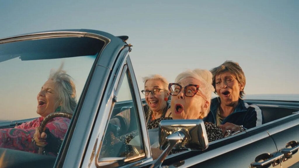 four women having a great time riding in a convertible car