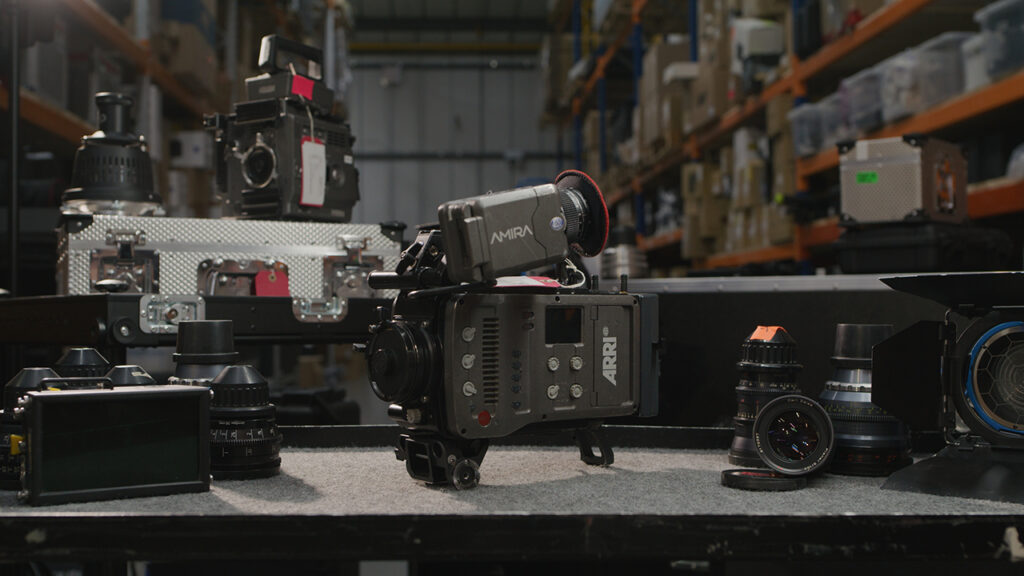 an ARRI camera rests on a shelf among several lenses in a warehouse