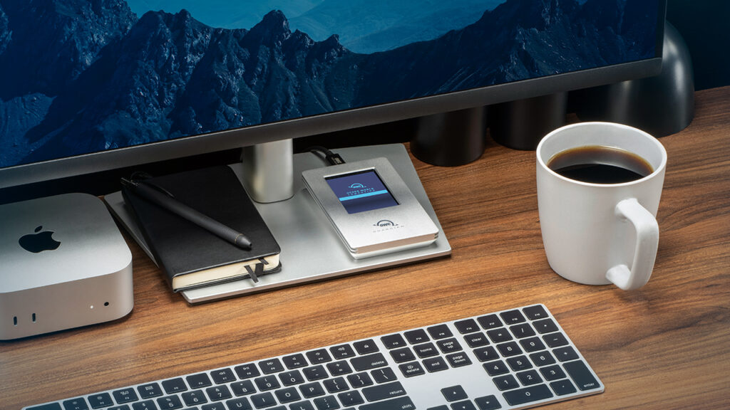 The OWC Guardian SSD lays on a desktop beneath the monitor of a computer