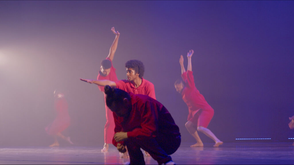 5 Brazilian dancers in red clothes dance on a dark stage
