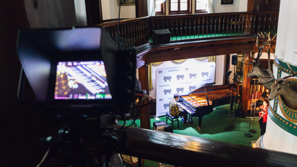 a piano player plays at the piano in the Chopin Festival while a Blackmagic camera films