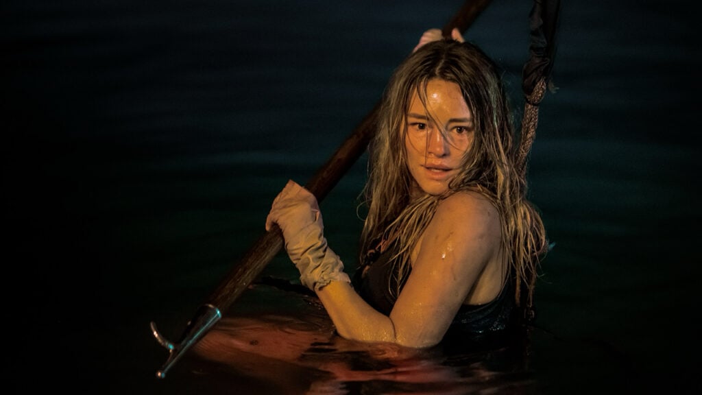 Hassie Harrison stars in a scene of the movie Dangerous Animals posed with a spear in the water