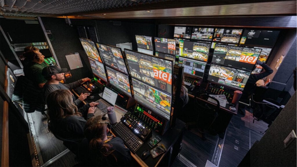 folks run a broadcast studio using equipment and staring at monitors
