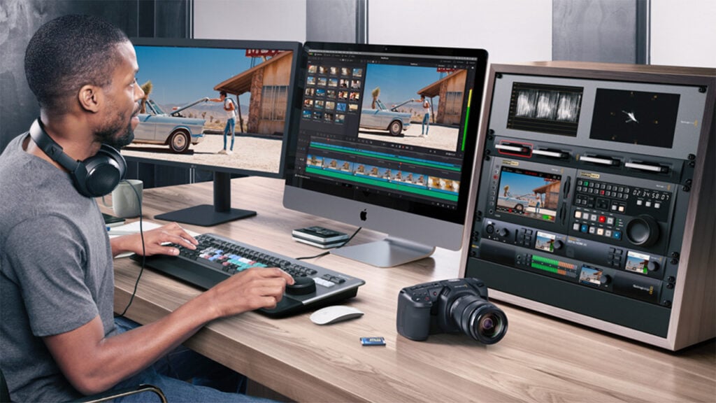 A man edits video on a computer with DaVinci Resolve showing on the screen