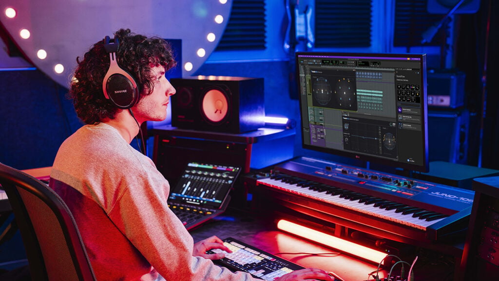 A man sits at a workstation with Avid's Pro Tools software displayed on the monitor