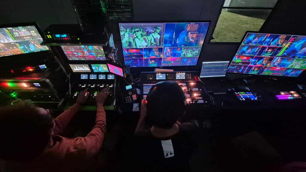 people sit in a darkened broadcast studio looking at monitors while producing the Lollapalooza concert