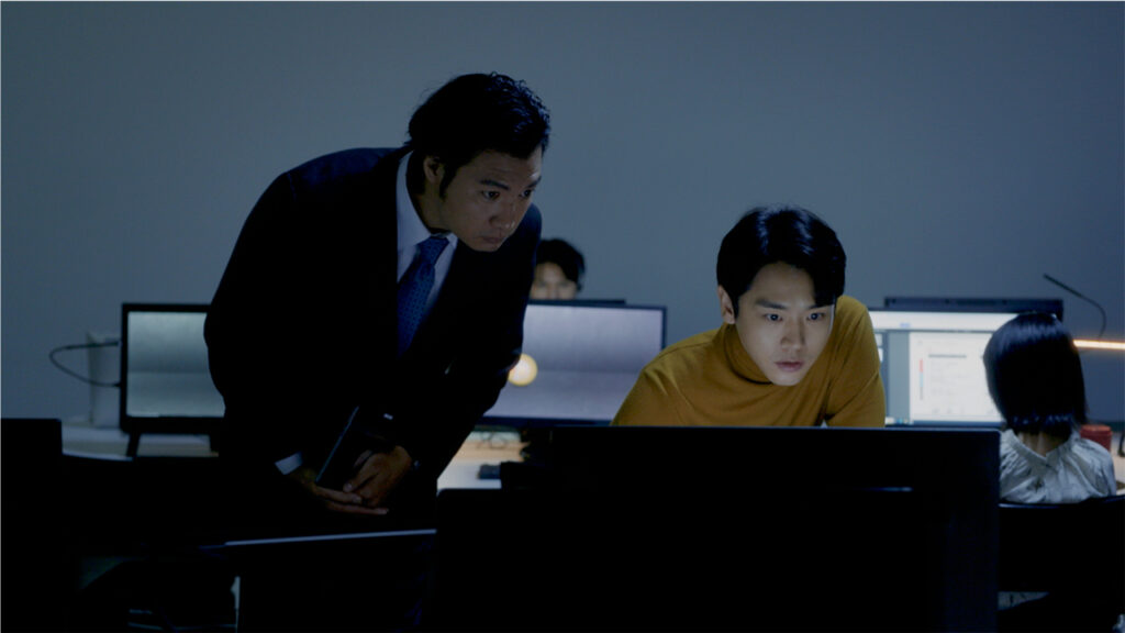 A man wearing a blazer stares at a computer screen with great concern