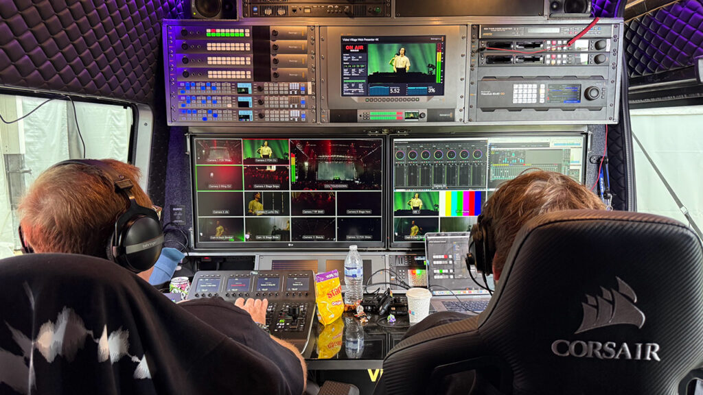 two fellows sit in a broadcast studio before several monitors and other equipment