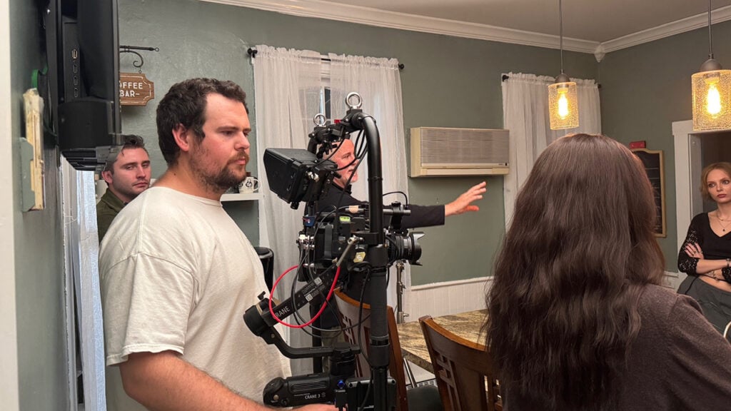 a cameraman holds a camera while filming an actress