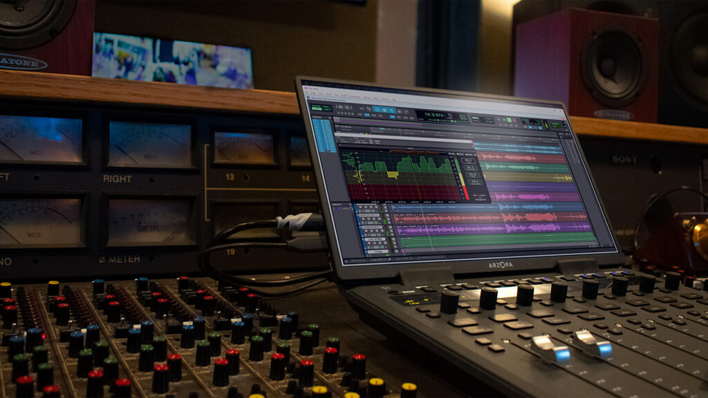 a computer rests on a sound board in an audio mixing studio
