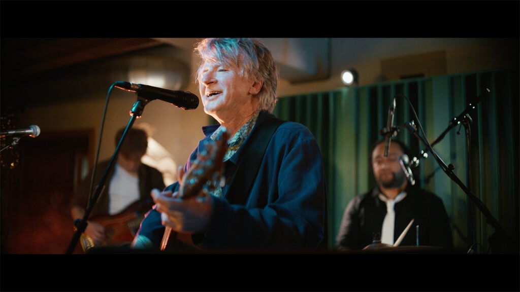 A man sings with his band on stage