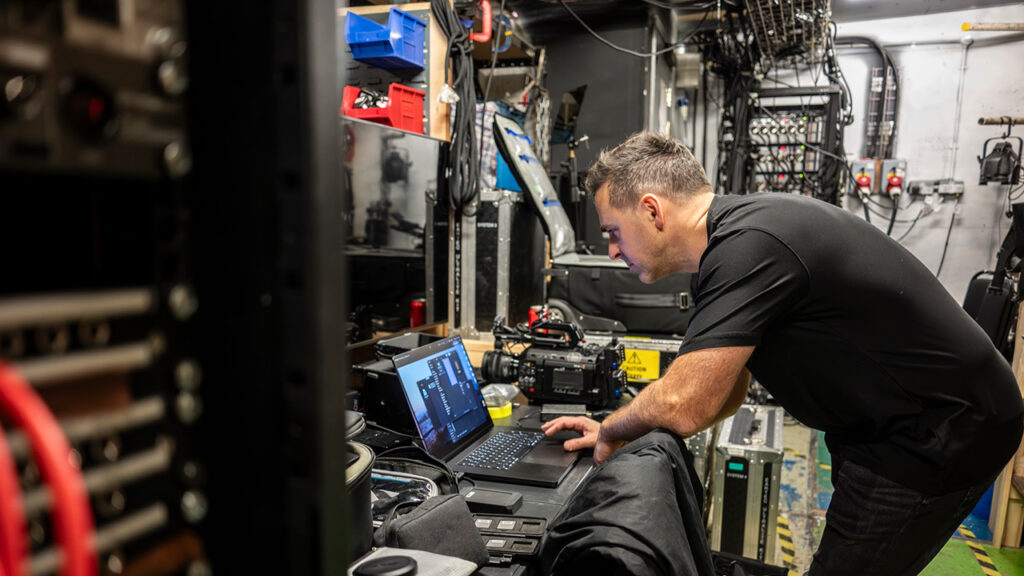 A man looks at a computer screen next to a Blackmagic URSA Cine camera