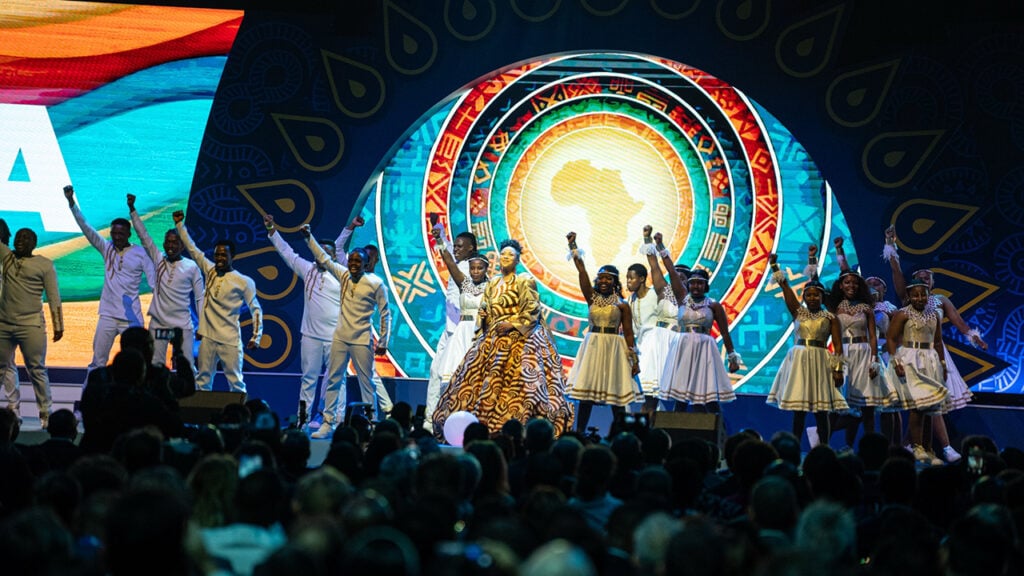 people sing and dance on stage before a crowd