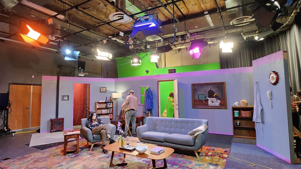 The set of a film is set up with a couch and lighting