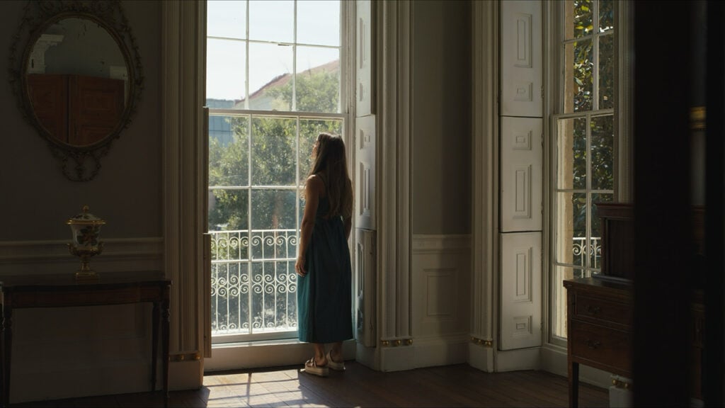 a woman stands looking out a window in a historic Charleston home