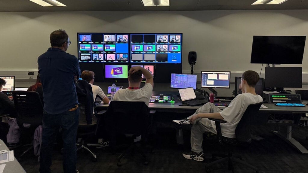 students sit in a broadcast studio looking at monitors