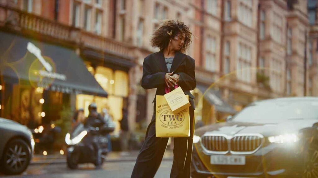 a woman stands in a street holding a bag of TWG tea