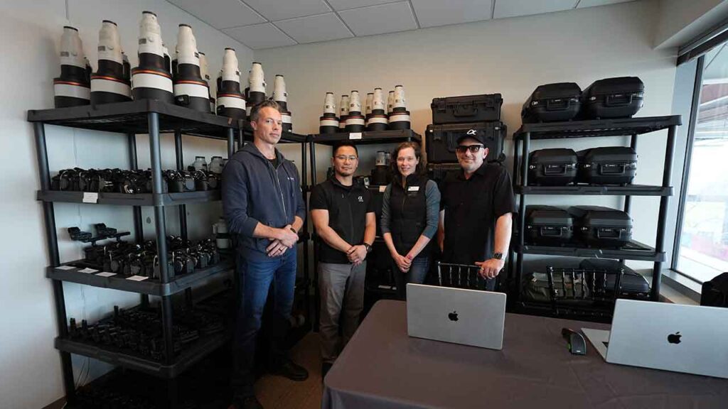 four people stand in a room filled with various lenses