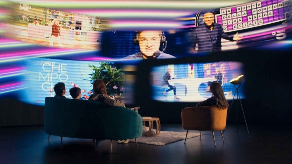 people sit on a couch surrounded by images from television programming