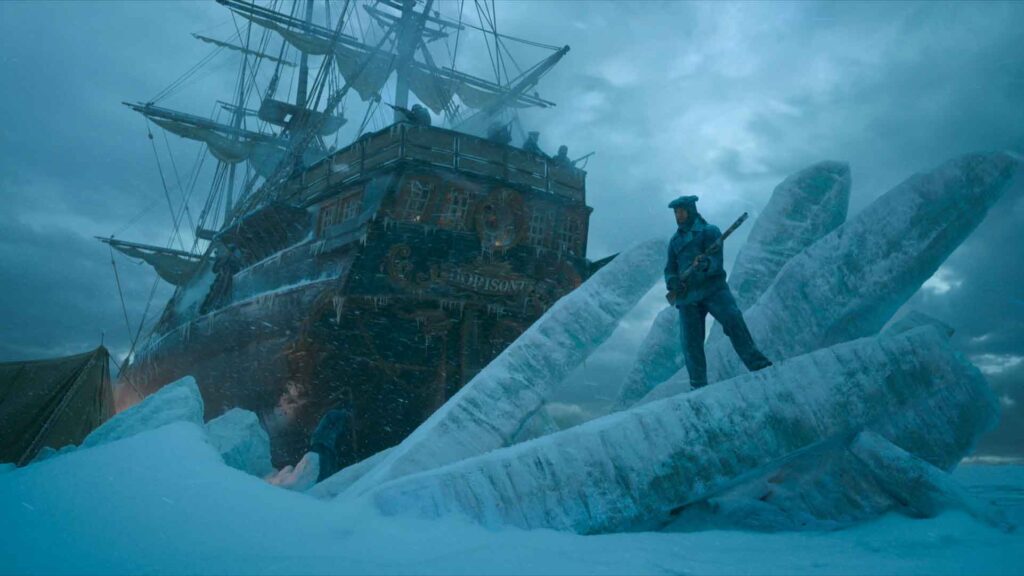 a man stands on ice next to a ship