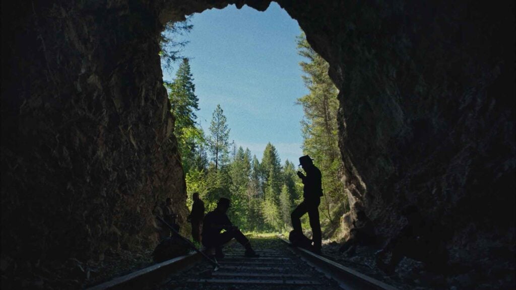 men stand on a railroad in a tunnel