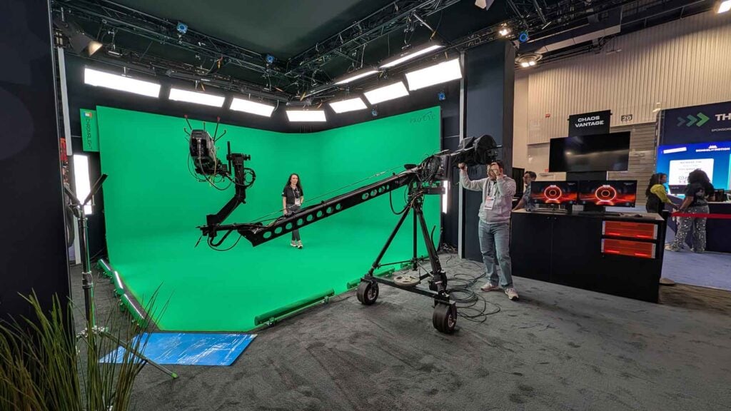 a woman stands on a green screen set while a camera films her