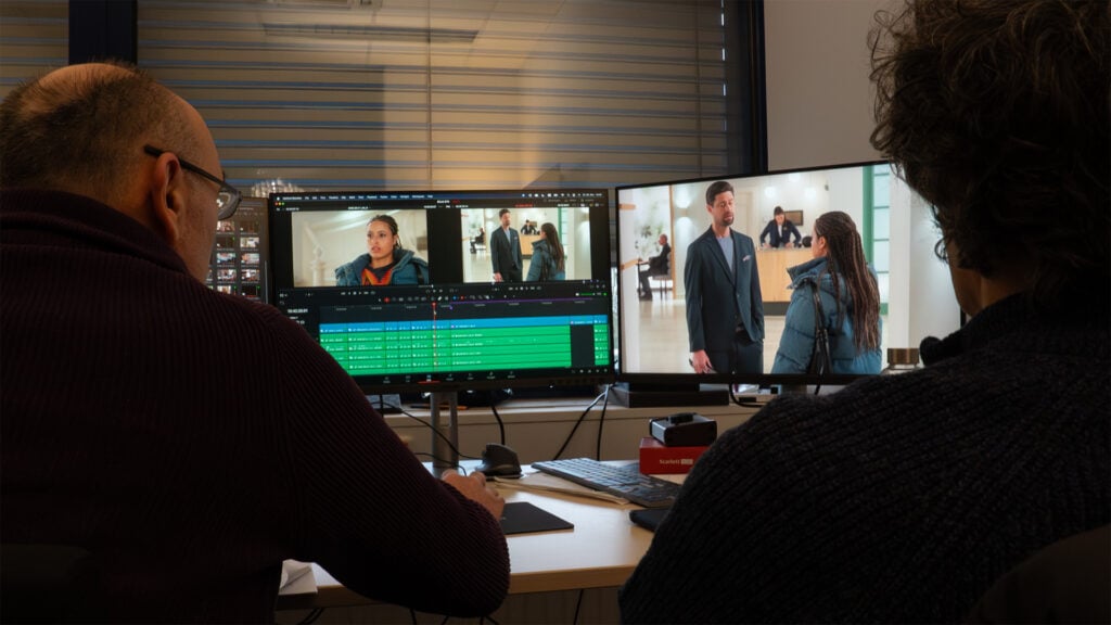 Two people stare at computer monitors while editing footage using DaVinci Resolve