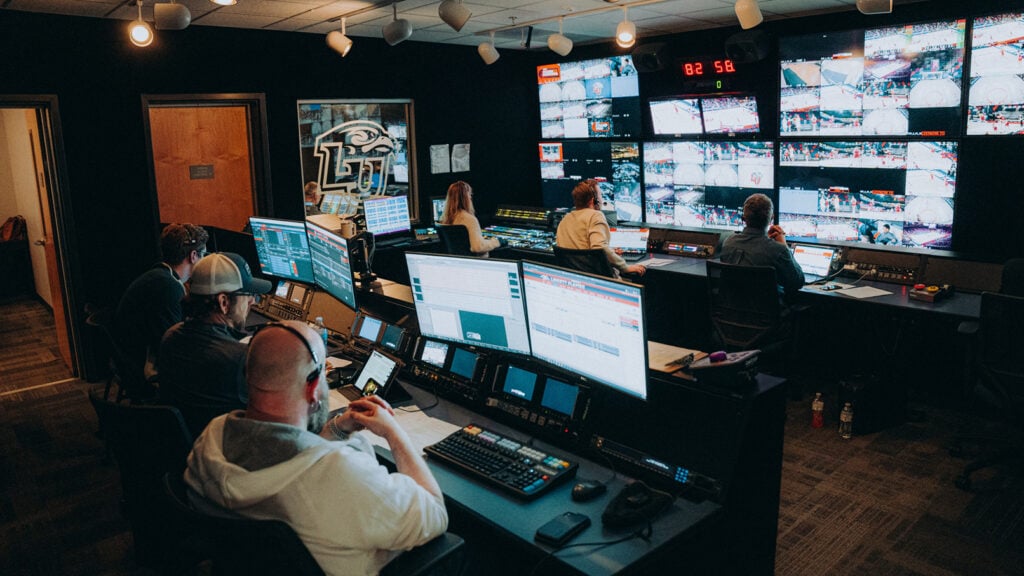 several people working in the broadcast room of a sports arena