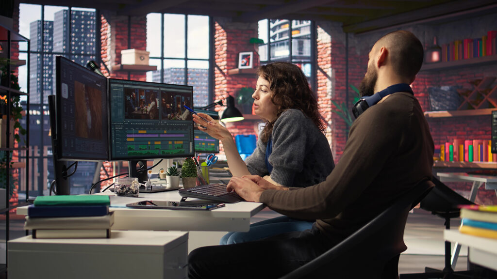 two people discuss footage they are editing on a computer