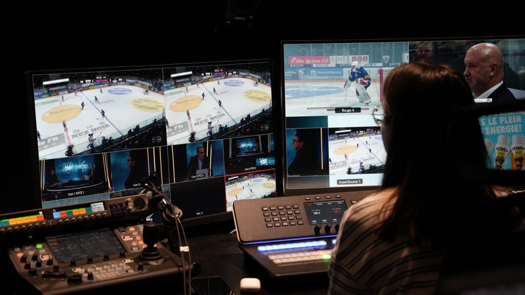 a woman works in a sports broadcast studio surrounded by monitors and production gear