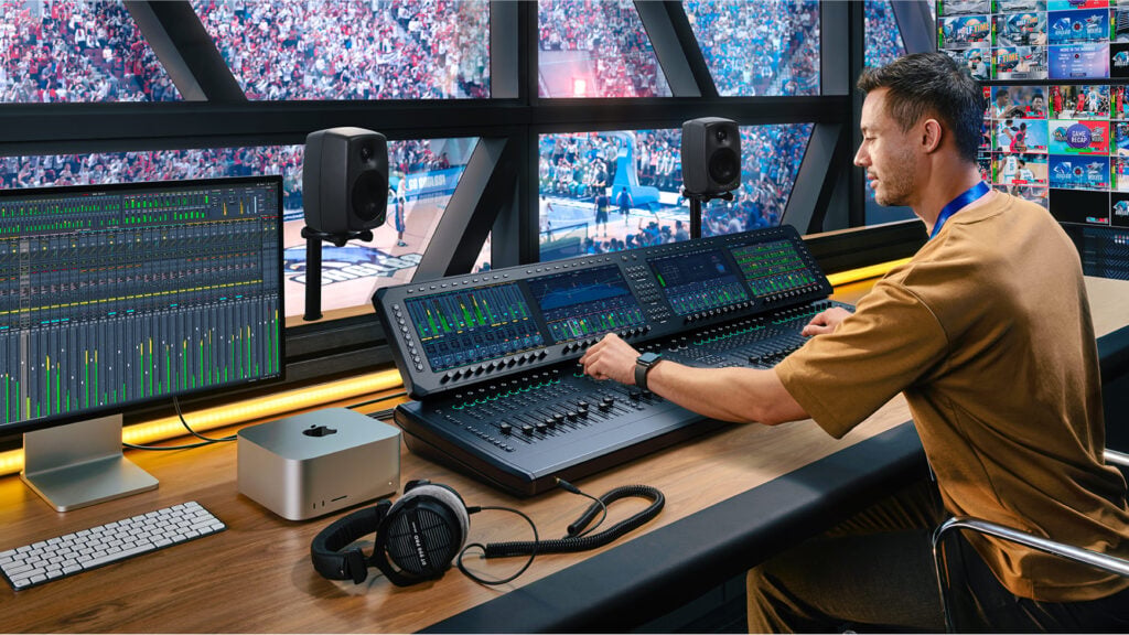 A man adjusts the controls while producing the audio for a basketball game using Blackmagic Fairlight Live