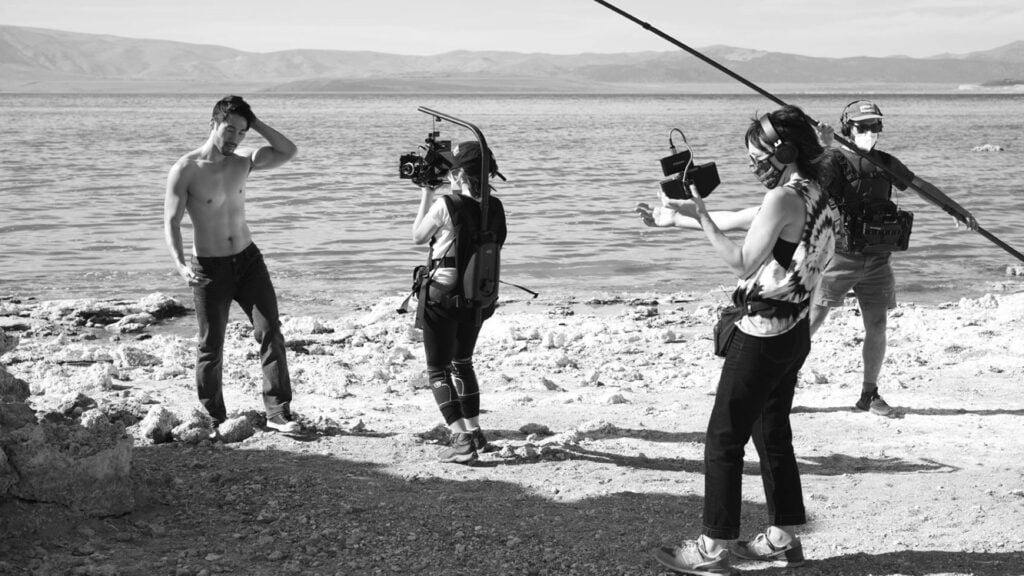 scene from an Indie Road Movie titled Where in the Hell where a man walks away from a body of water while a camerawoman Shoots the scene with Pocket Cinema Camera 4K