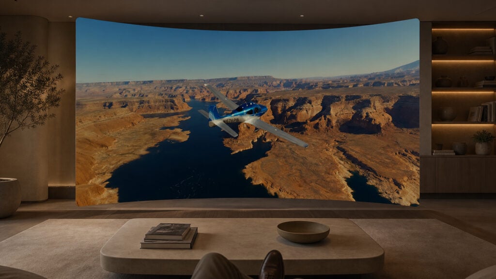 a curved television screen displays a small airplane flying over the Grand Canyon