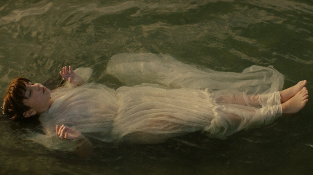 a woman in a white dress floats in water