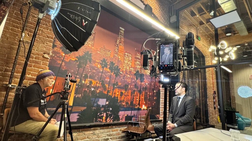 A man sits on set surrounded by lighting and Blackmagic Design production gear Photo Credit: Isabella Vosmikova