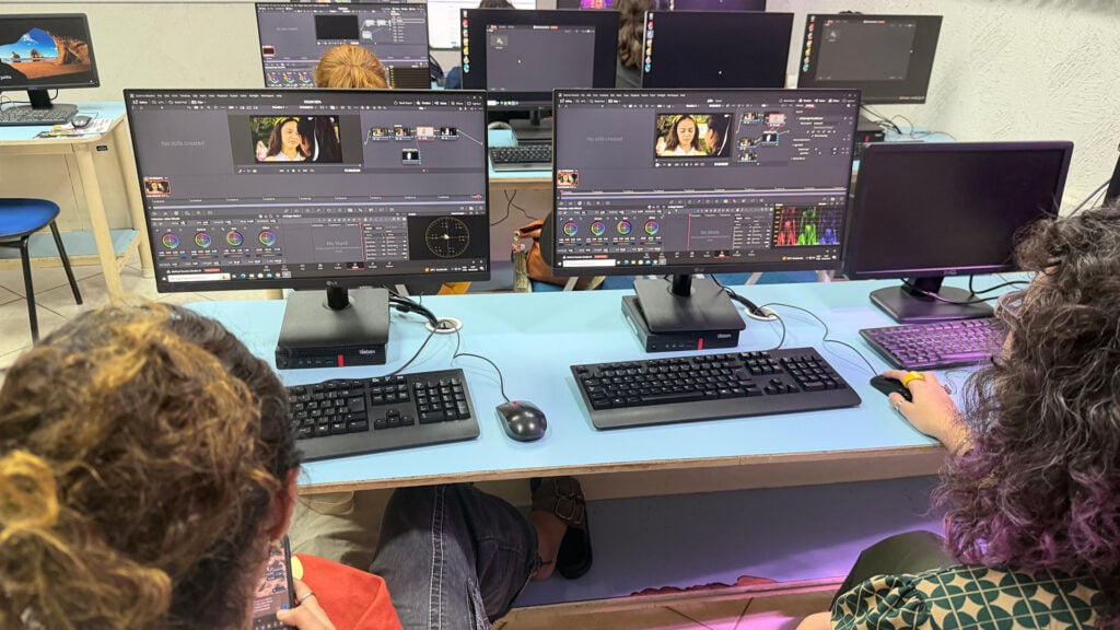two women edit video footage on computers using DaVinci Resolve Studio in a classroom